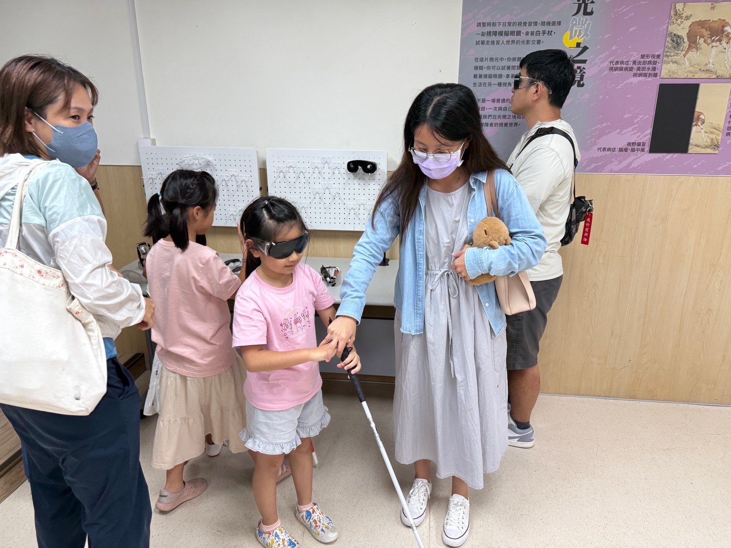 一位女生在教導一位小朋友體驗盲人的VR技術